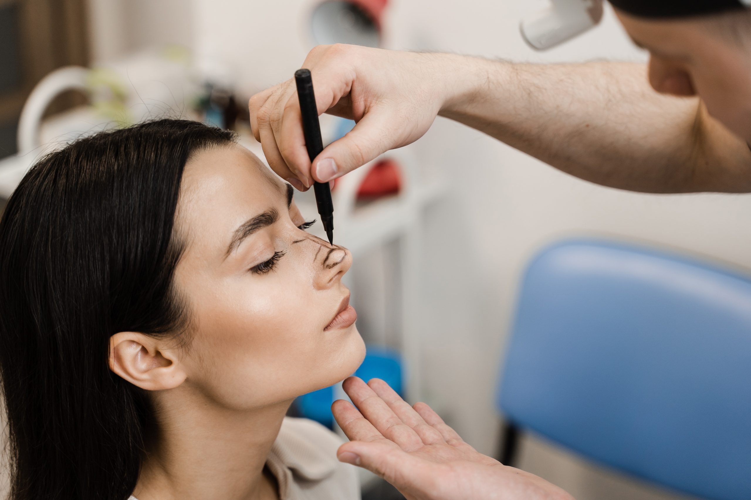 Doctor drawing lines on a woman's nose in preparation for rhinoplasty surgery.